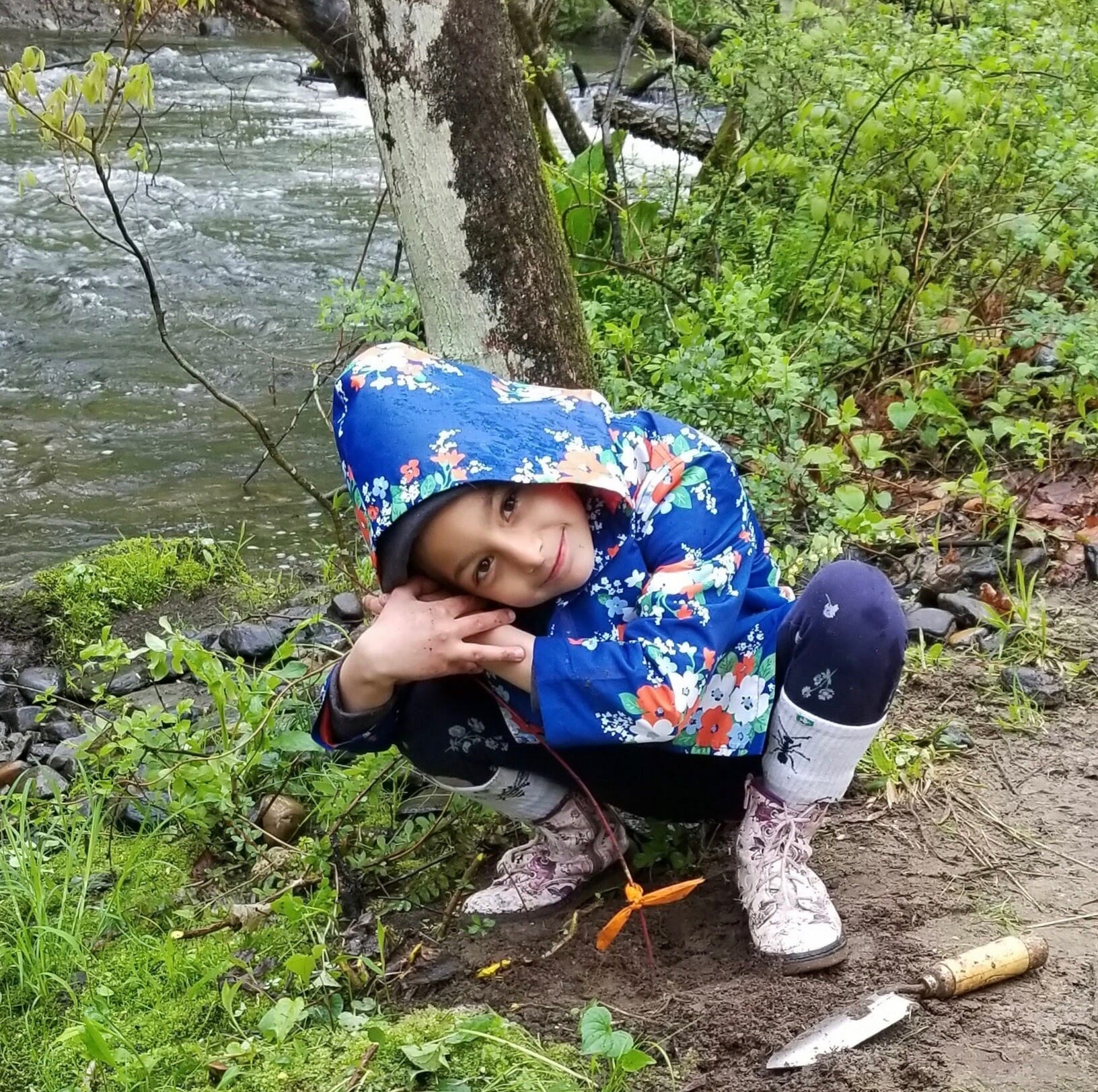 A little girl plants a tree along New York trout stream