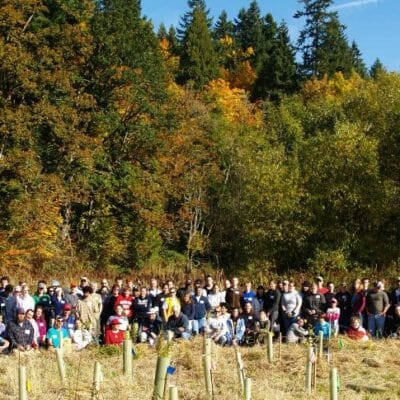 A group of volunteers poses behind newly planted trees.