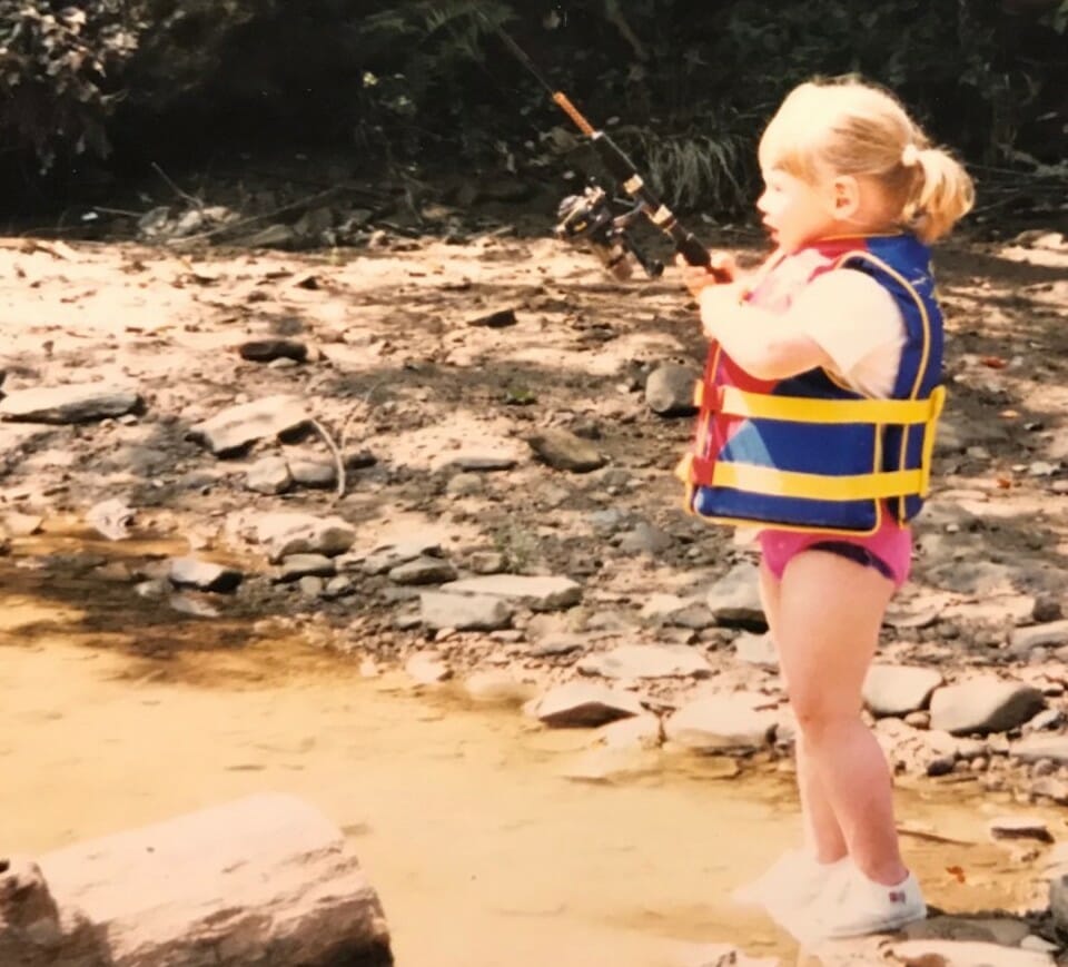 A young girl casts a spinning rod for trout in West Virginia.