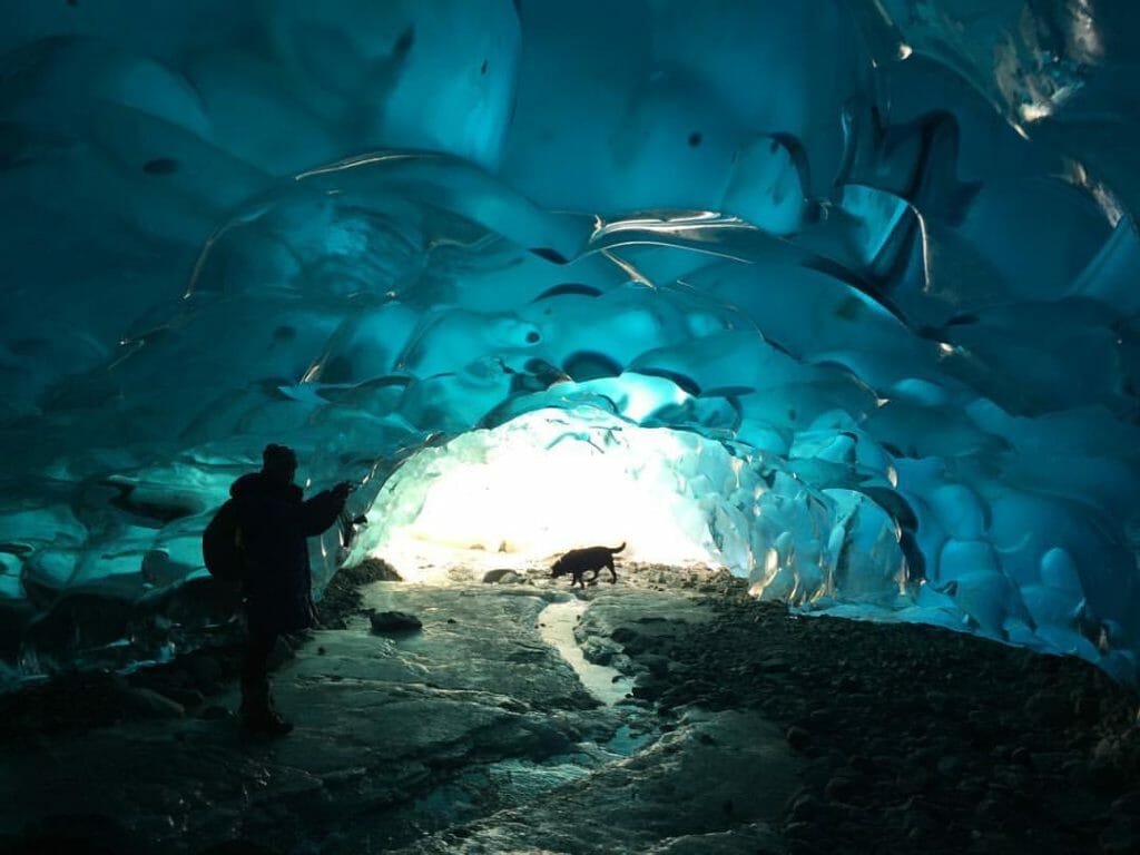 A woman and her dog explore an ice cave near Juneau, Alaska. 