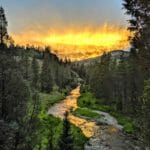 A trout stream running through a canyon at sunset.