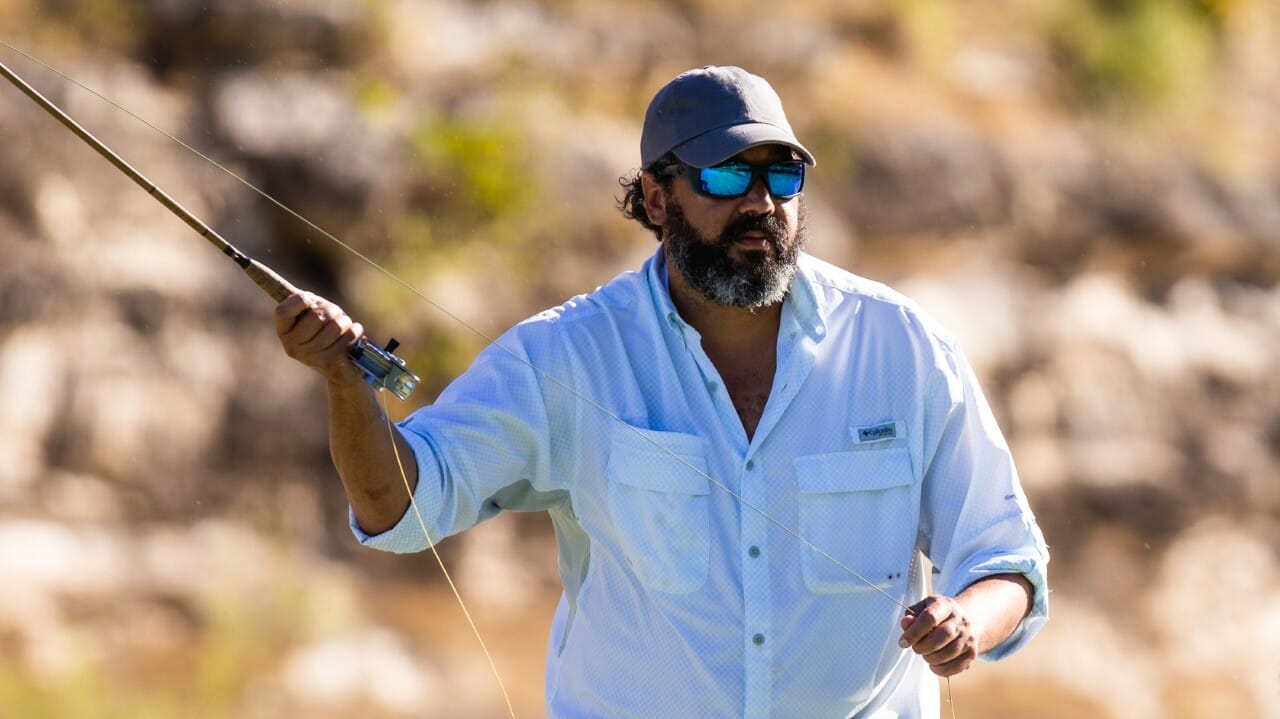 An African-American man fly fishes