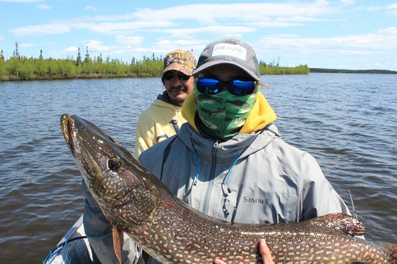 A boy holds a big northern pike.