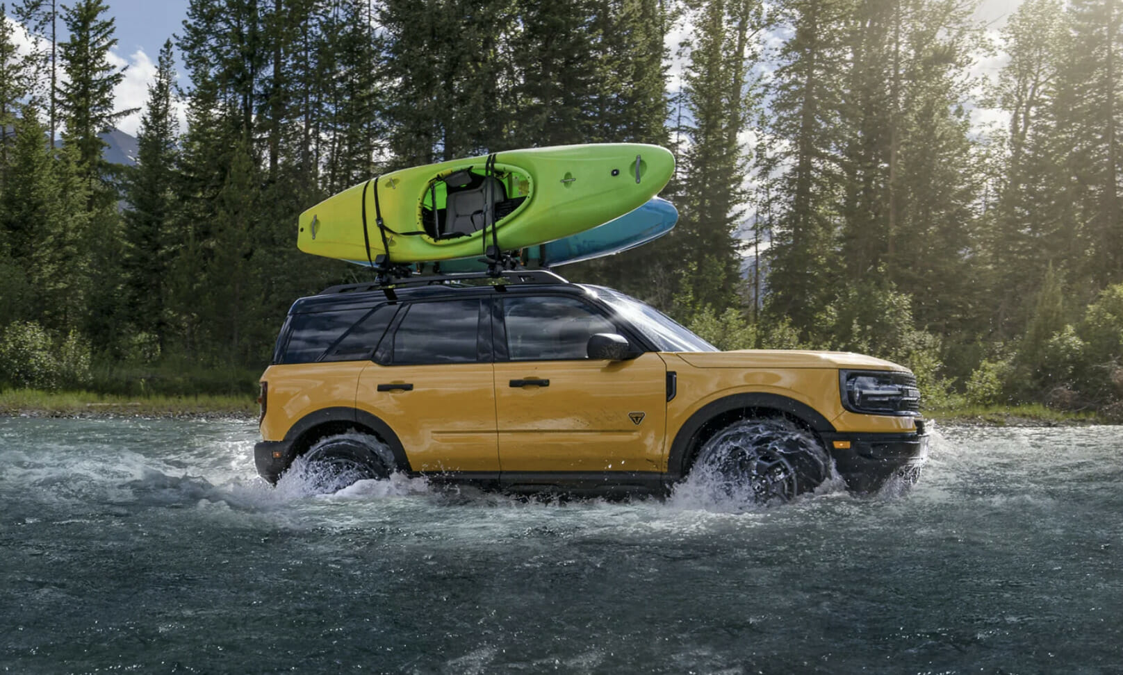 A Ford Bronco drives through a river.