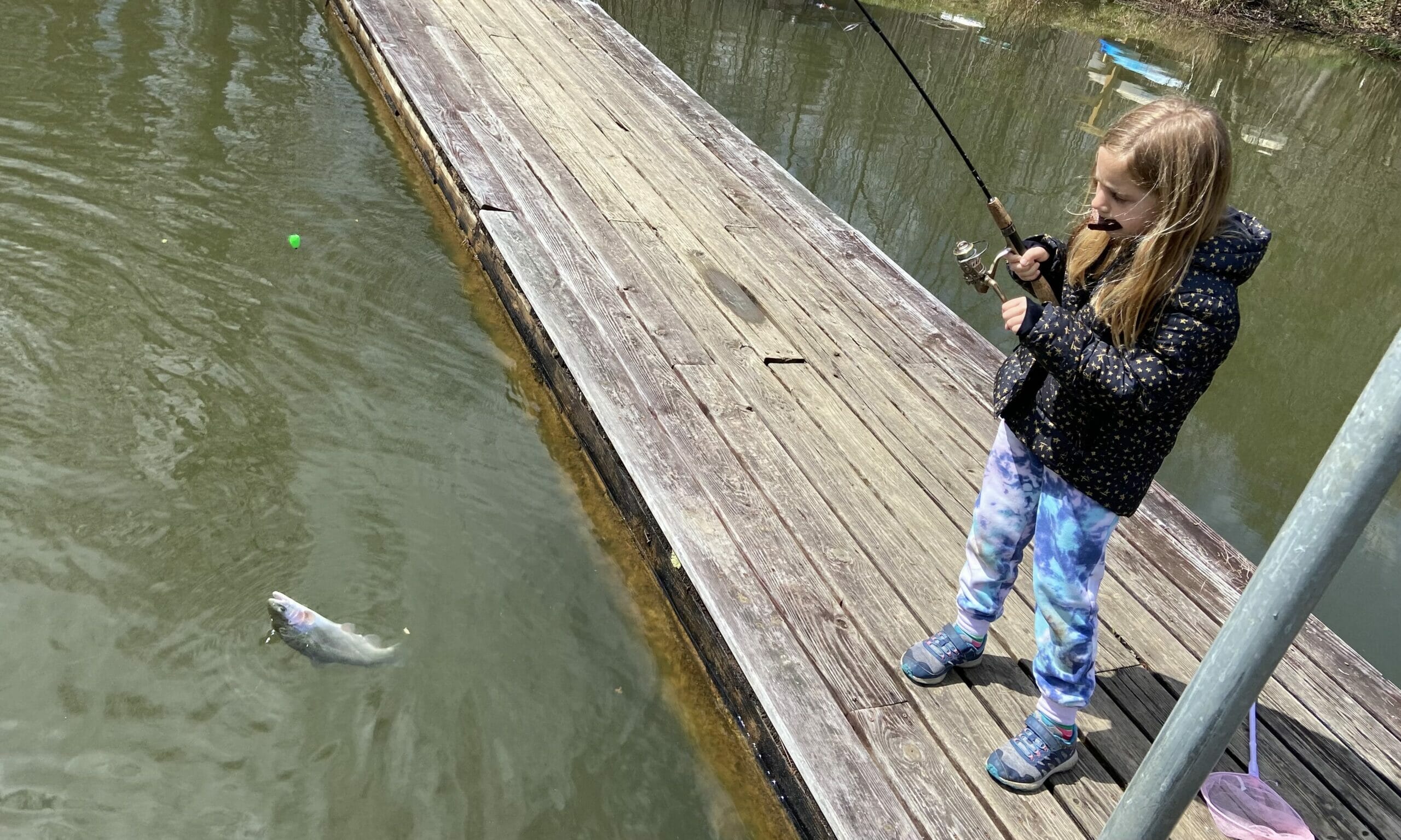 Girl on a dock with fish on end of line