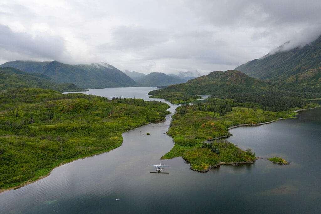 Plane landing on water by cloud covered mountains