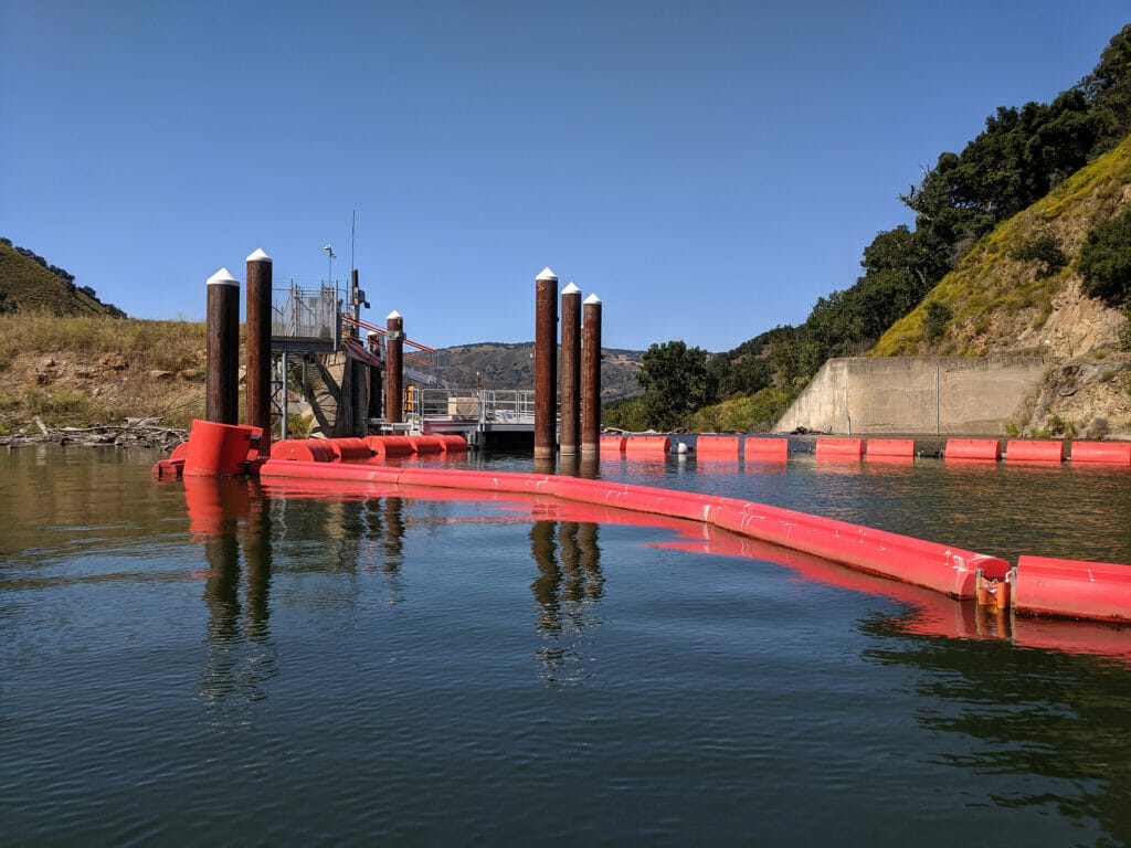 Red buoy-looking objects on the water surface encompass the damn bypass boundaries