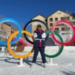 Olympian, Eric Loughran, standing on snow, in front of large Olympic rings
