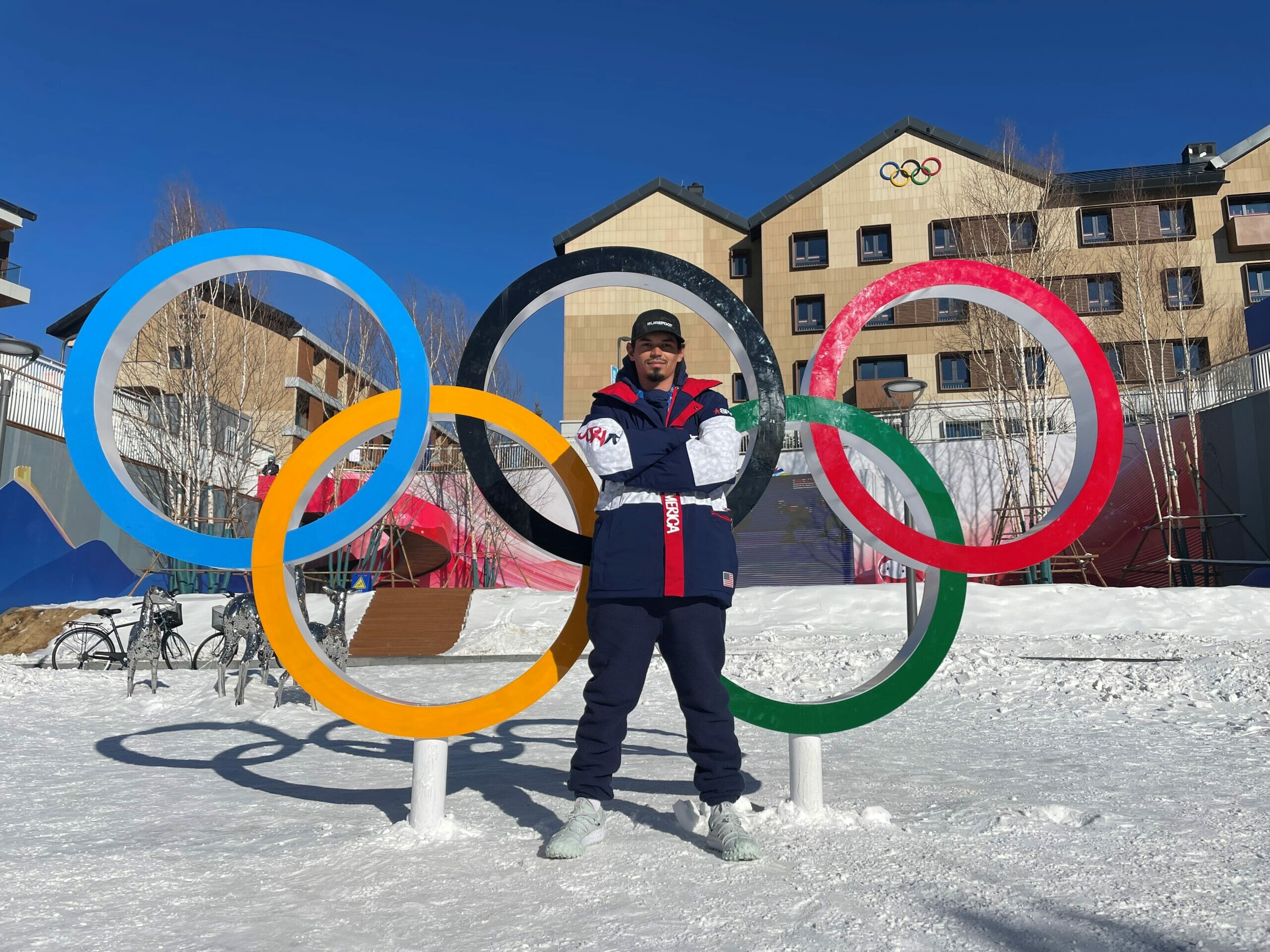 Olympian, Eric Loughran, standing on snow, in front of large Olympic rings