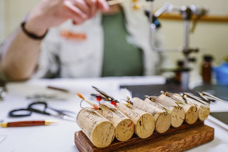 Several flys being tied, hooked to corks