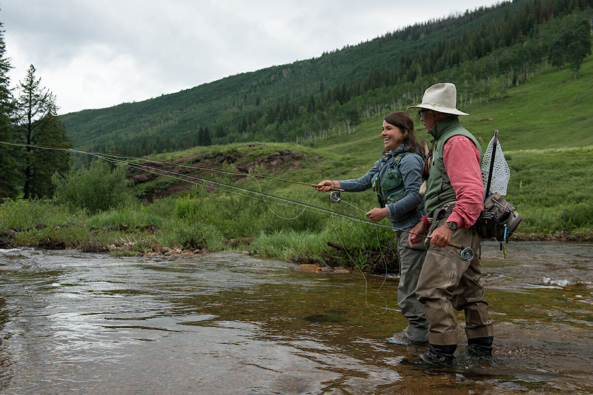 Young woman and older man fly fishing in a river