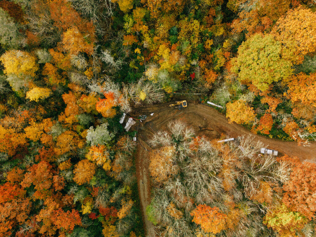 Aerial view of vehicles and equipment working to improve Infrastructure on winding dirt road