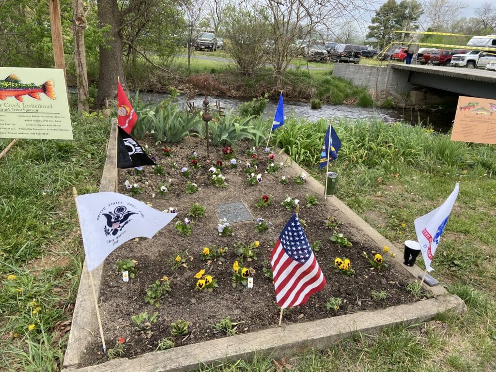 Flower bed with service military flags and a plaque.