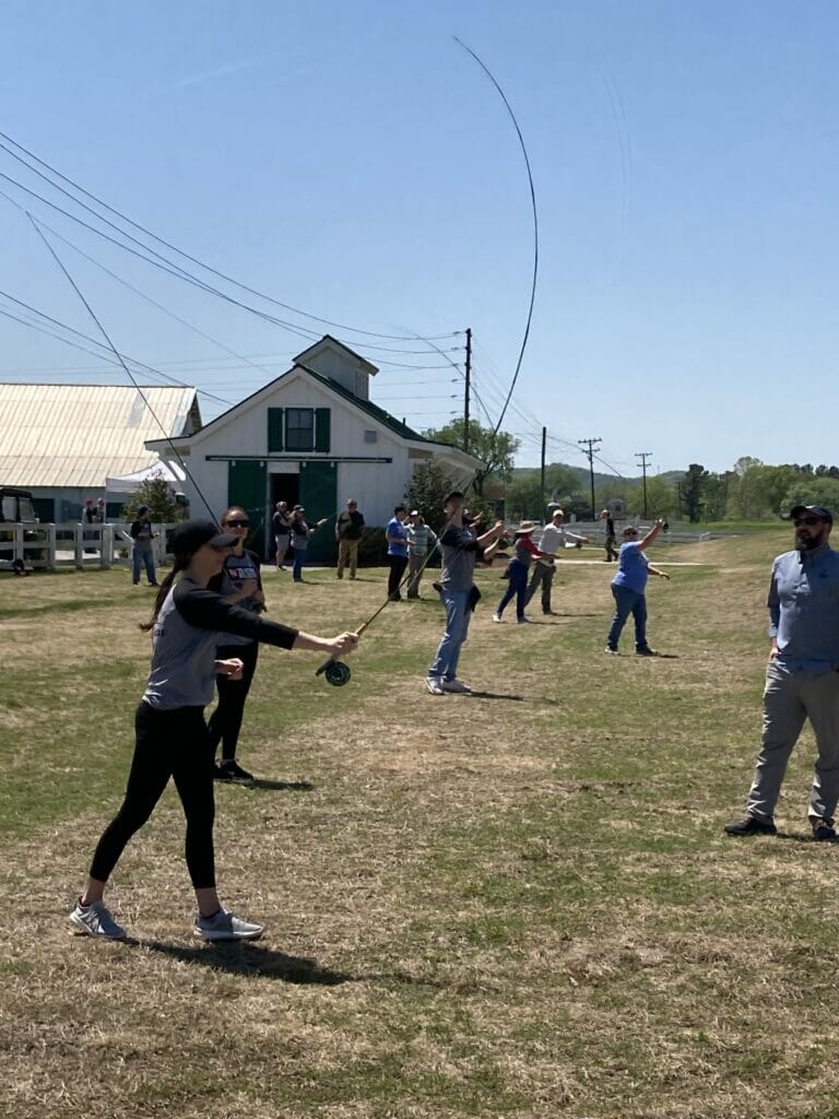 View from the side of people practice fly casting in a field