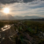 Sun shining from behind clouds over beautiful mountains and river