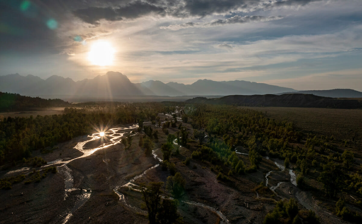 Sun shining from behind clouds over beautiful mountains and river