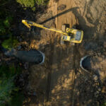 Backhoe next to a culvert on a dirt road