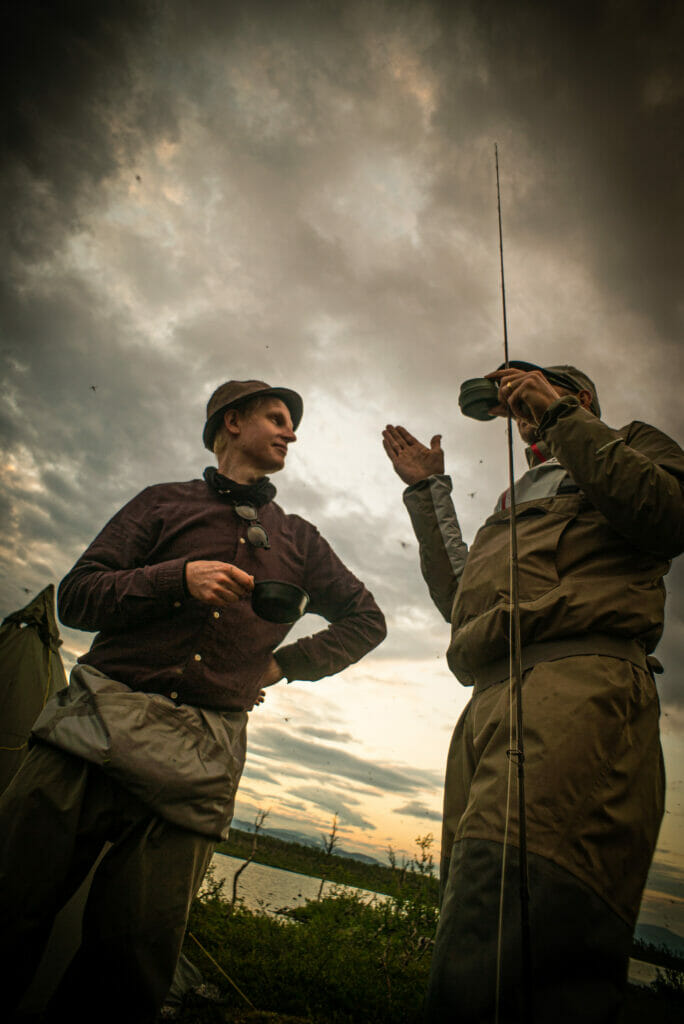 Two fishermen talk while drinking coffee