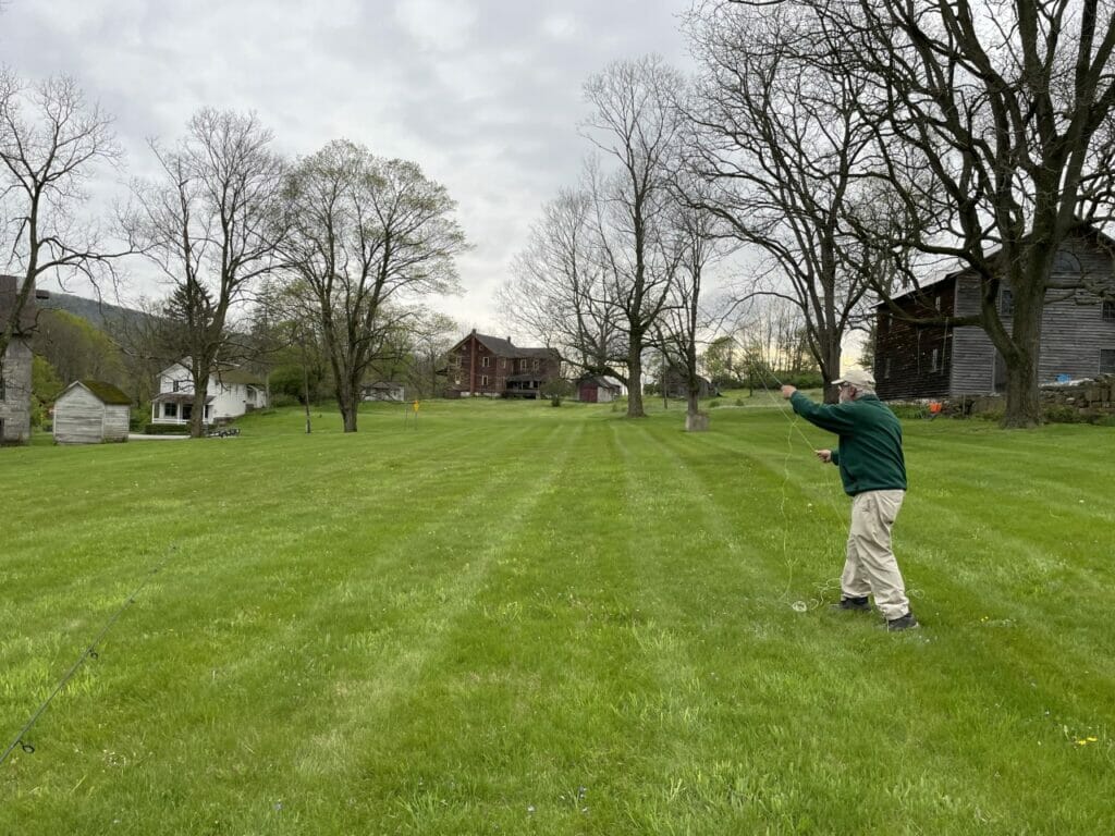 Old man, Dave Rothrock, practices casting in grassy yard