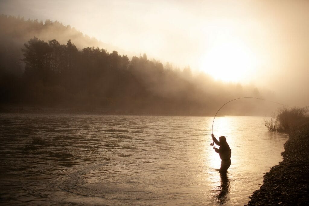 Silhouette of a man casting during a hazy sunrise