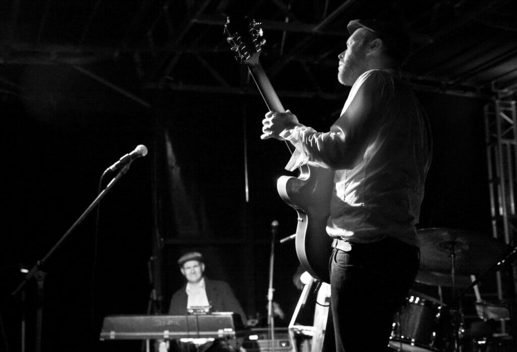 Black and white photo of man playing jazz guitar shot from behind