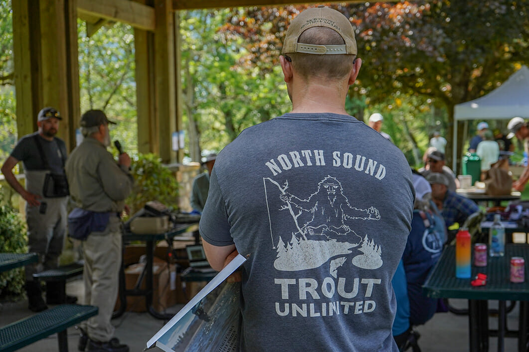 Man at gathering who's shirt reads "North Sound Trout Unlimited" and shows a sasquatch