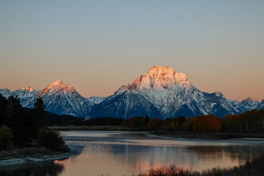Bend of a river in front of snow capped mountain during sunset
