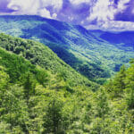 View of mountain forrest valley with billowing clouds