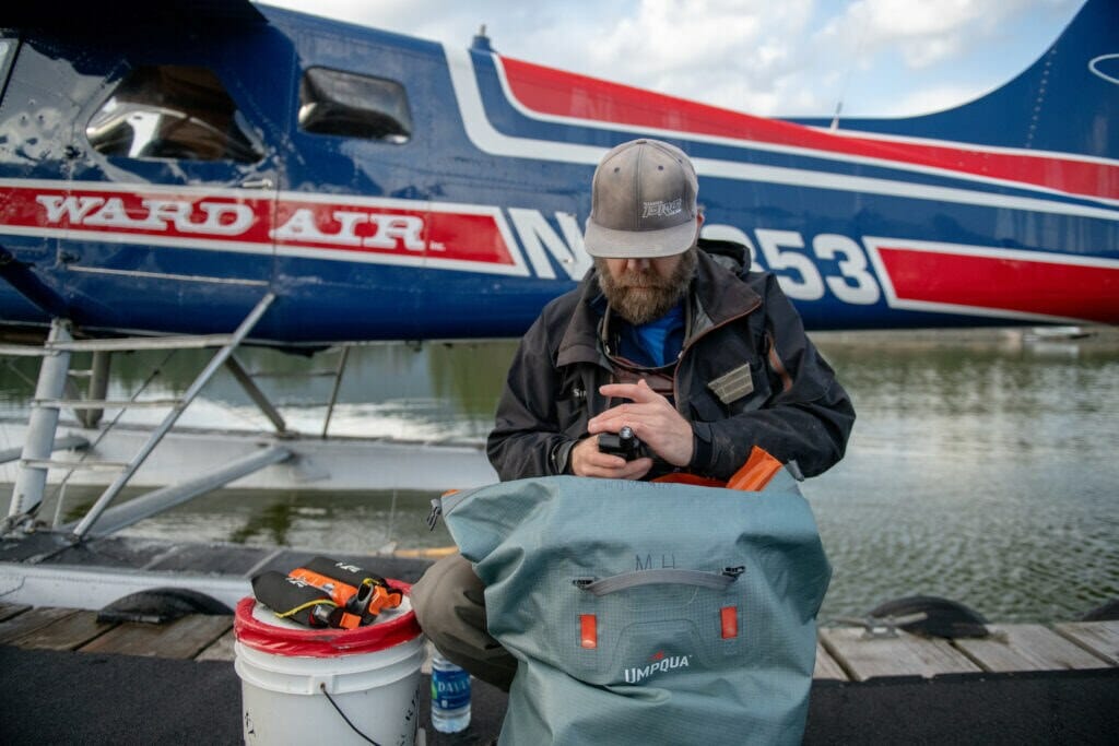 Bearded man looks at his equipment sitting on dock next to plane