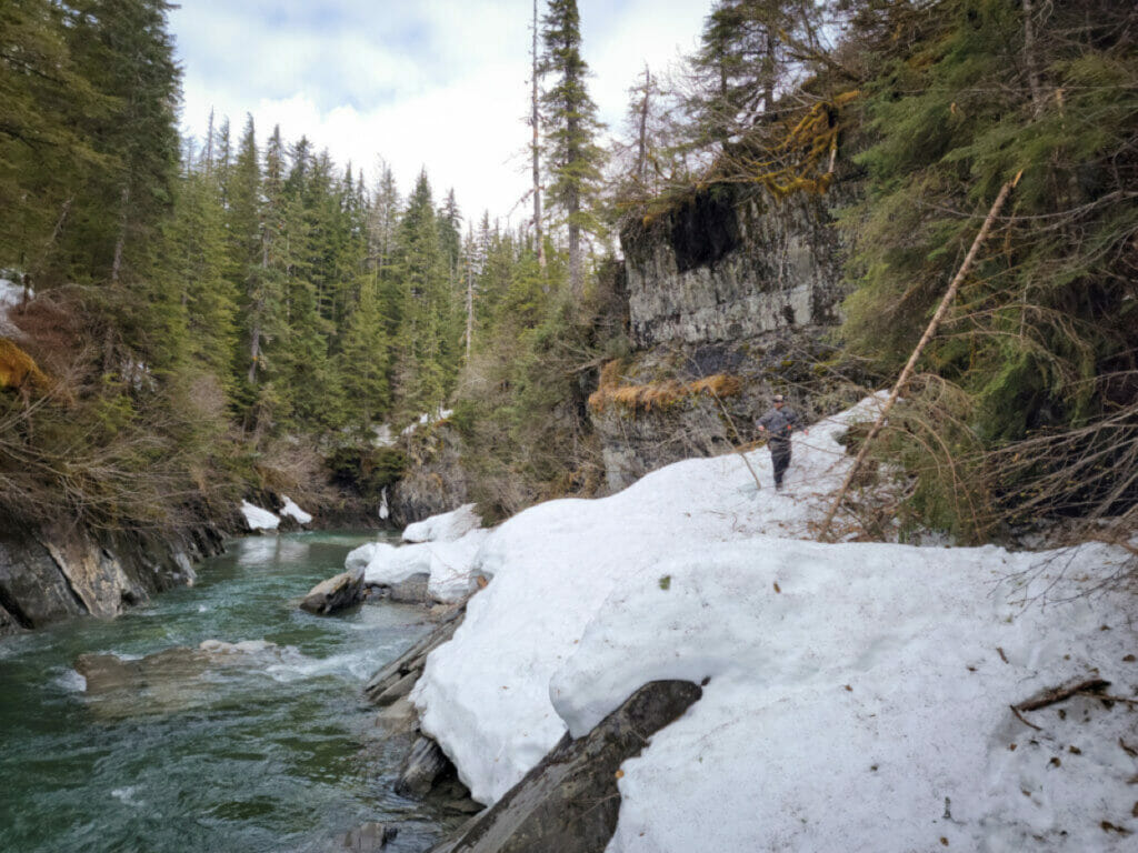 Man walks on snow next to river