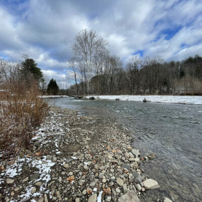 Stream with rocks on bank surrounded by snow covered ground