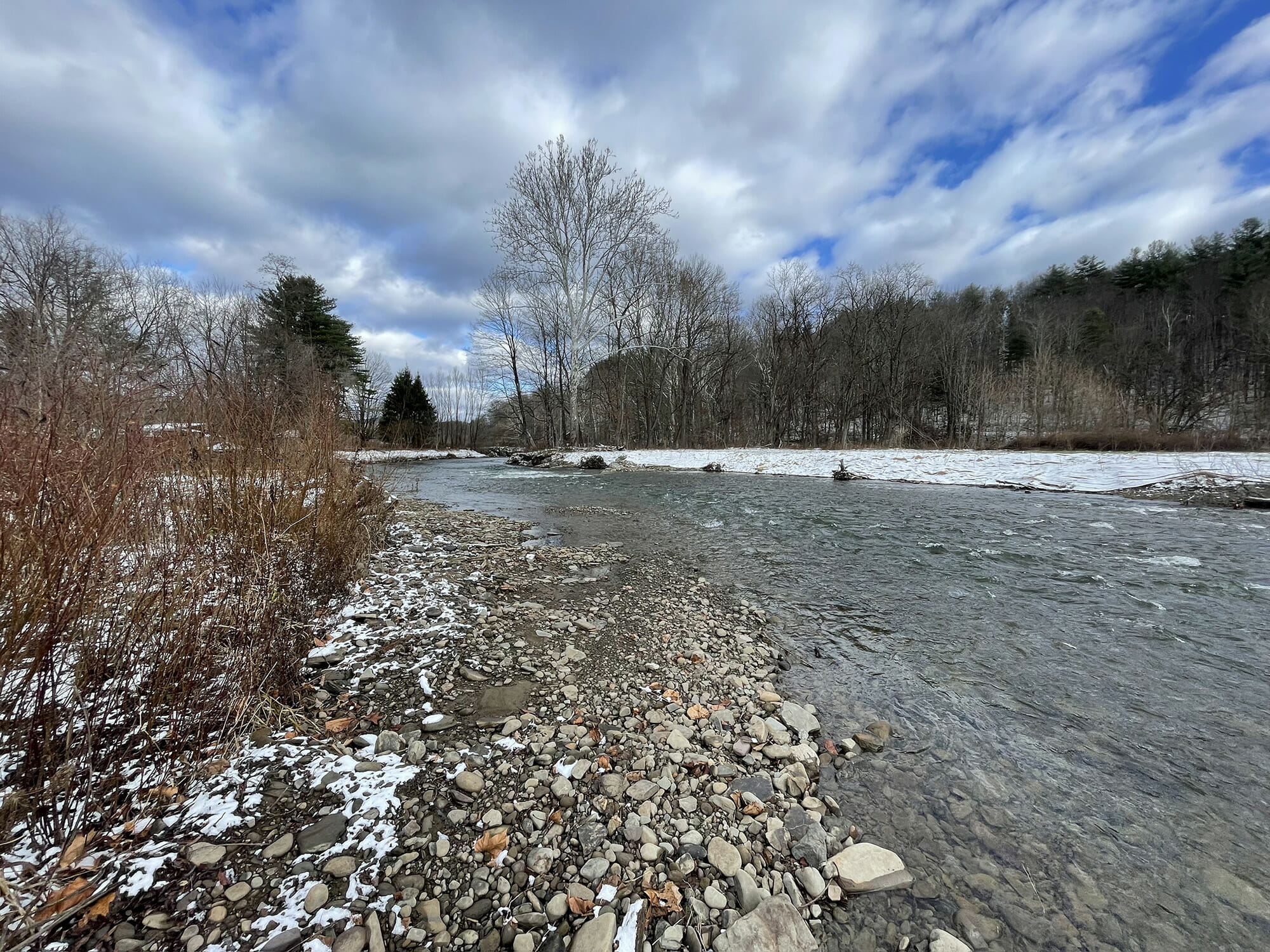 Stream with rocks on bank surrounded by snow covered ground