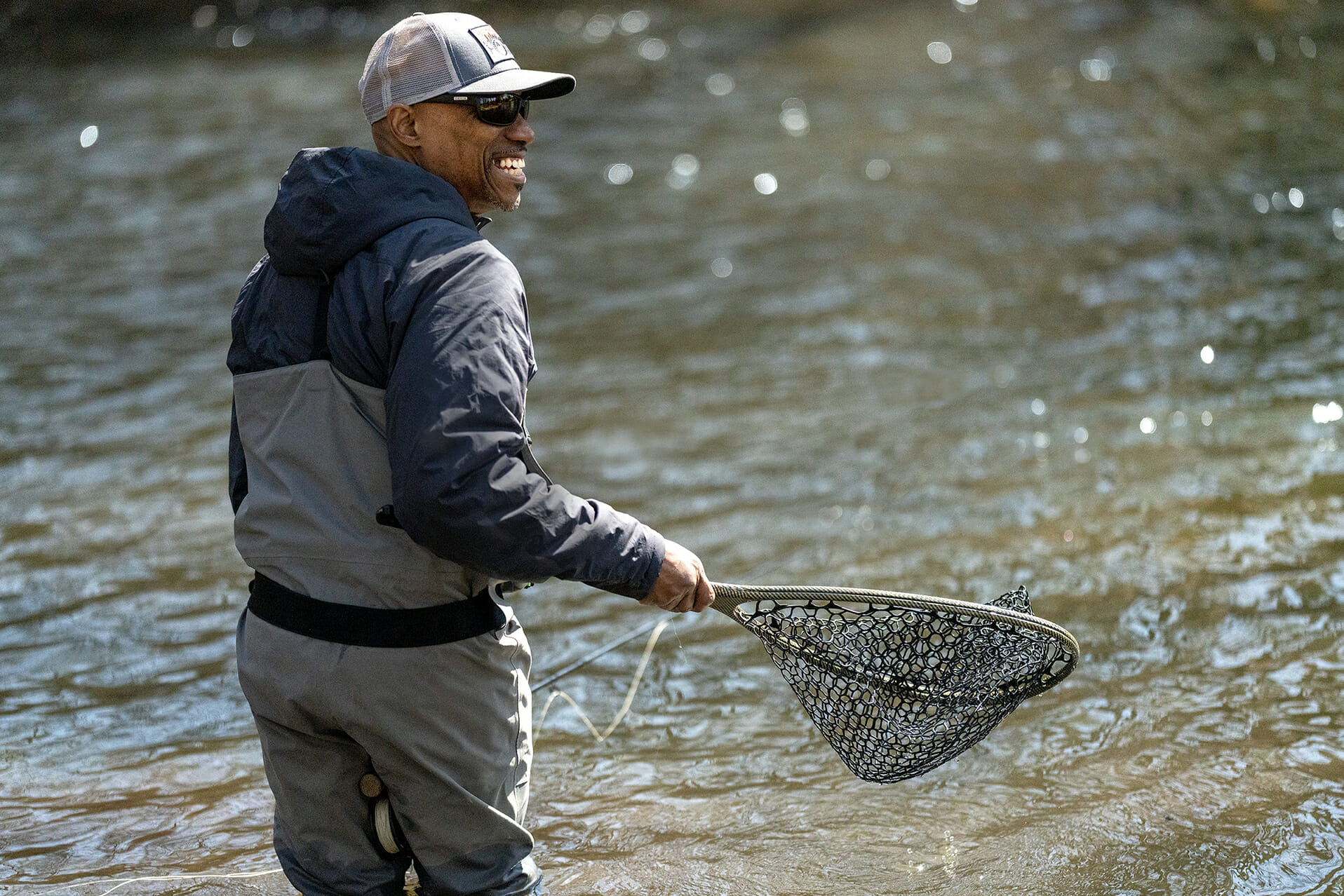 Smiling man holds a net next to a river