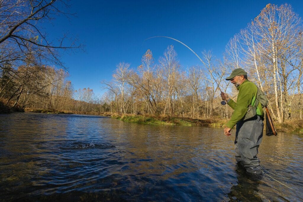 Man standing in a river catching a fish