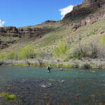 Man in the distance fishing in a wide river