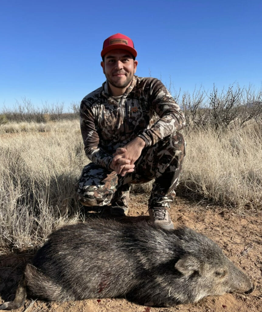 A man crouches next to a dead animal