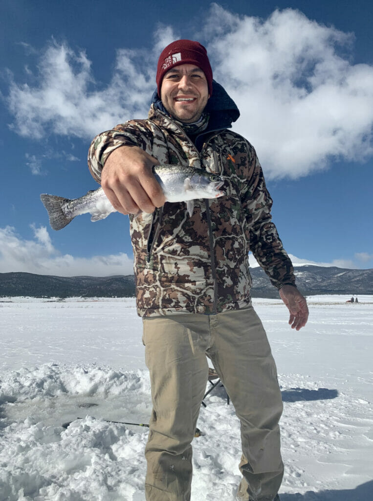 An ice fishing man holds up a fish for the camera