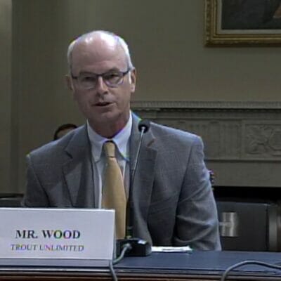 Chris Wood sits at a table speaking into a microphone