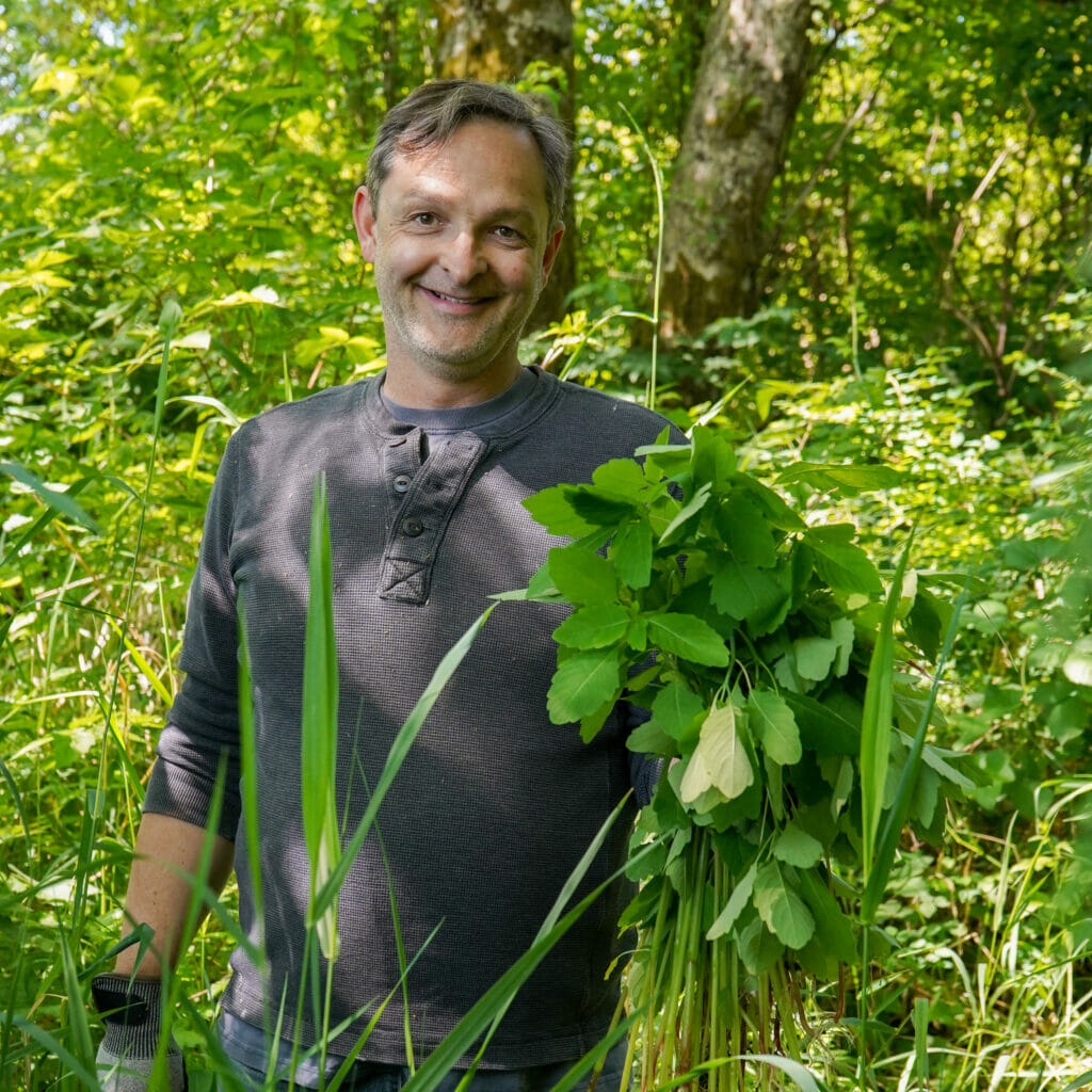 Smiling main holding some plants in the woods