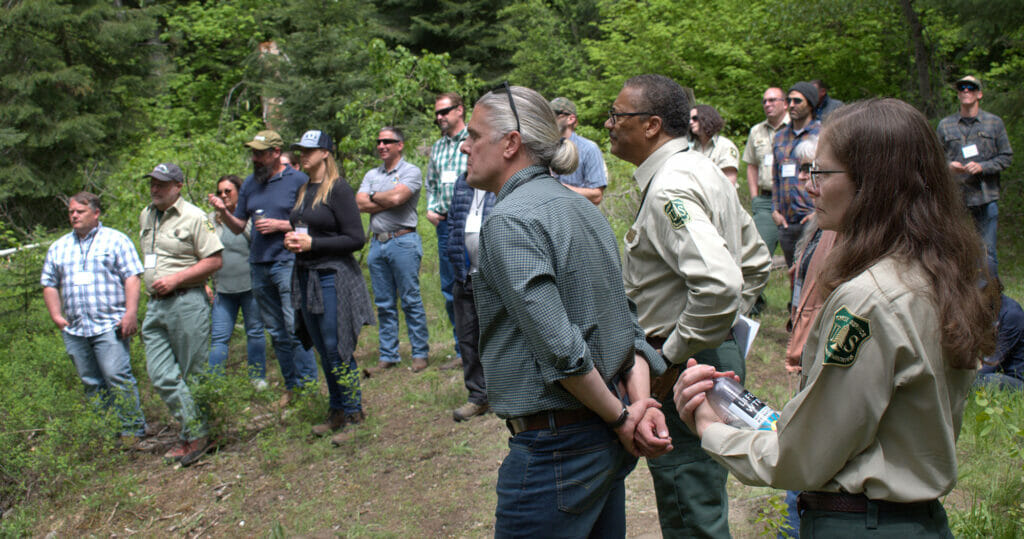 Group of people in the woods listen to a presentation