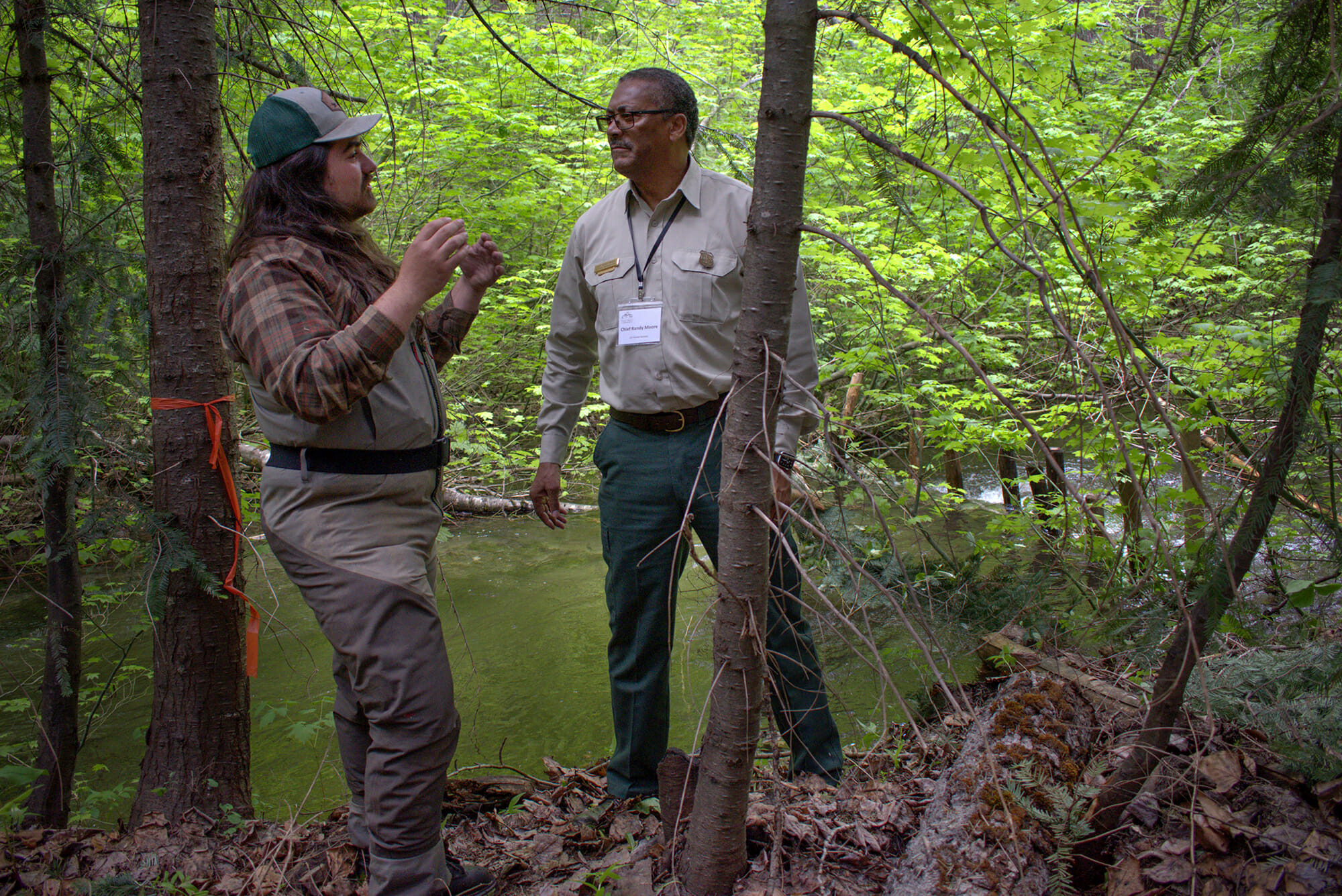 Two men have conversation next to a stream