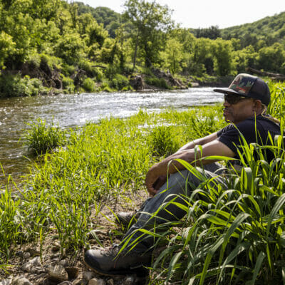 Man sits in grass watching the river