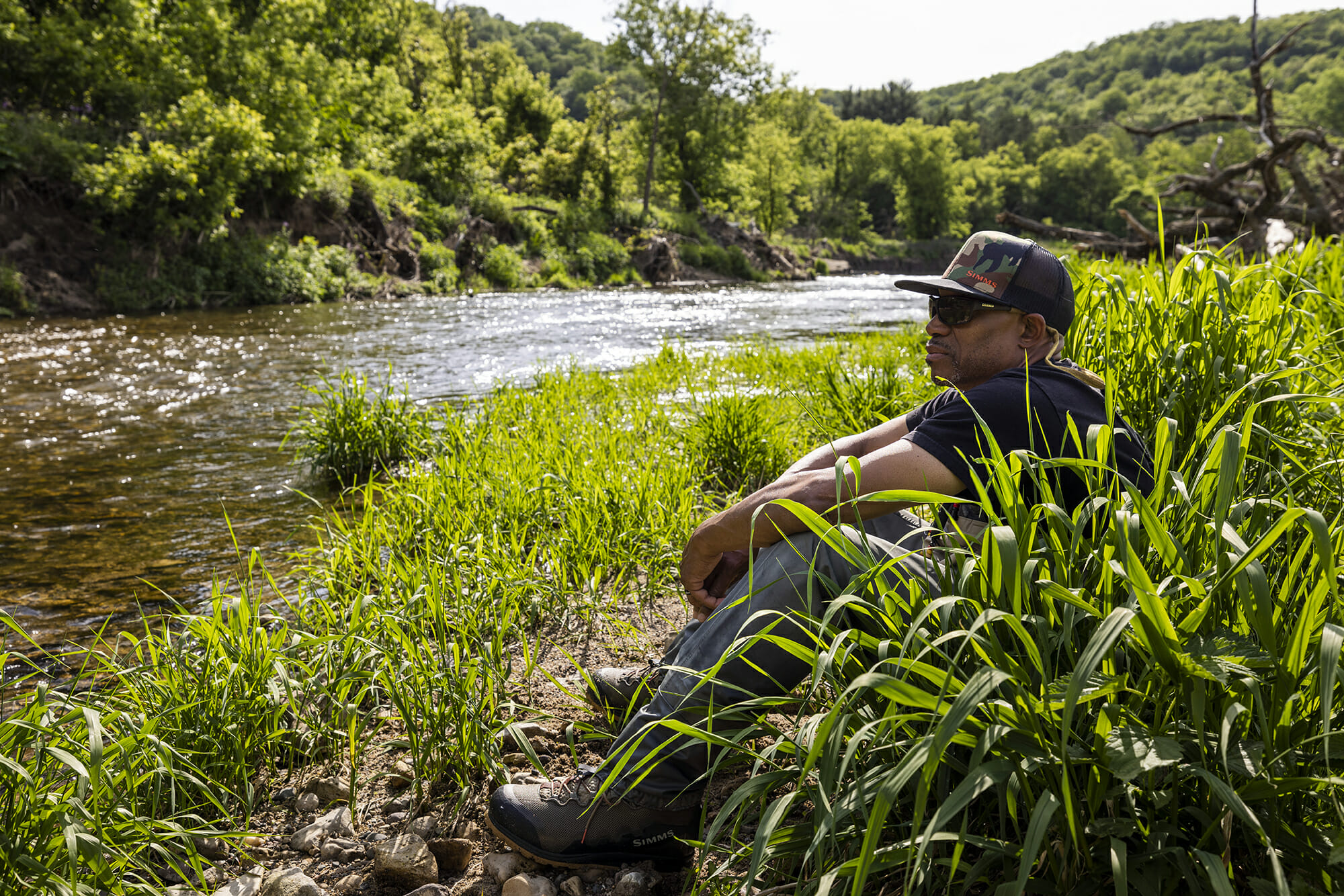 Man sits in grass watching the river