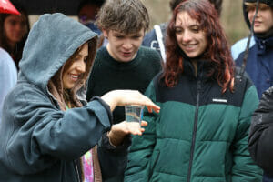 On a rainy day students hold a jar containing a small fish