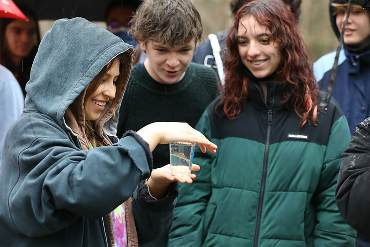 On a rainy day students hold a jar containing a small fish