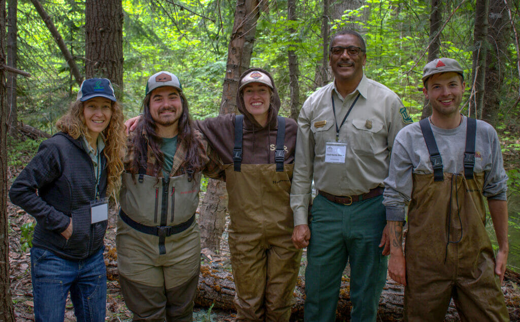 Group of outdoorsy-looking people smile at the camera in the woods thinking about fire resilience