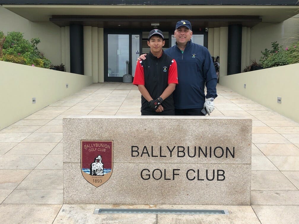Father and son stand in front of sign reading "Bullybunion Golf Club" thinking about Golf and Fly Fishing