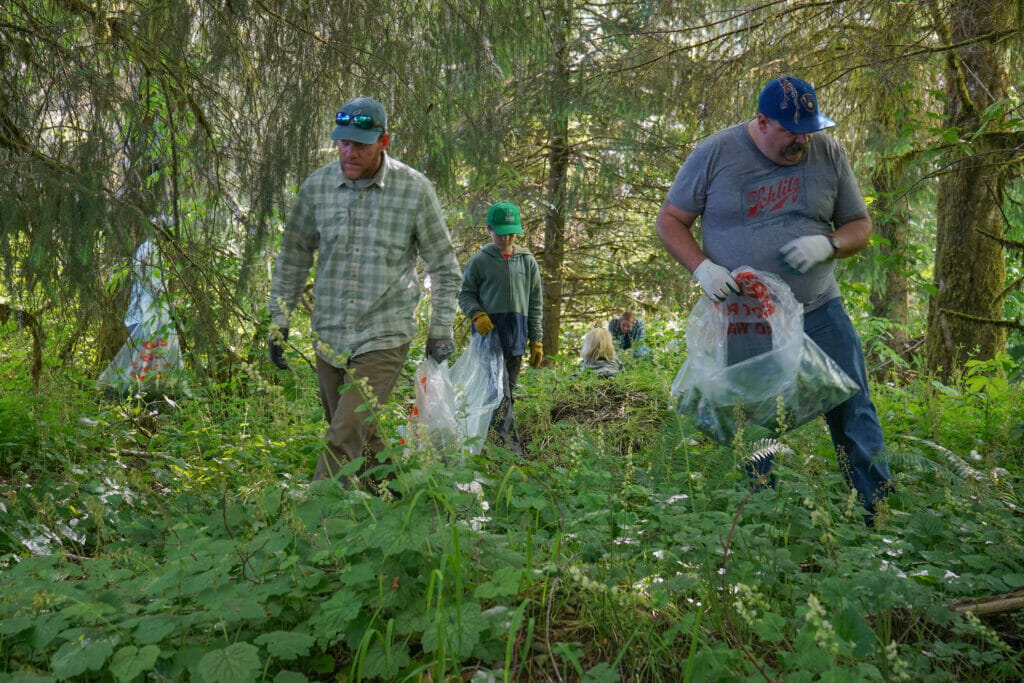 Men and a kid in the woods hunting for weeds in the woods