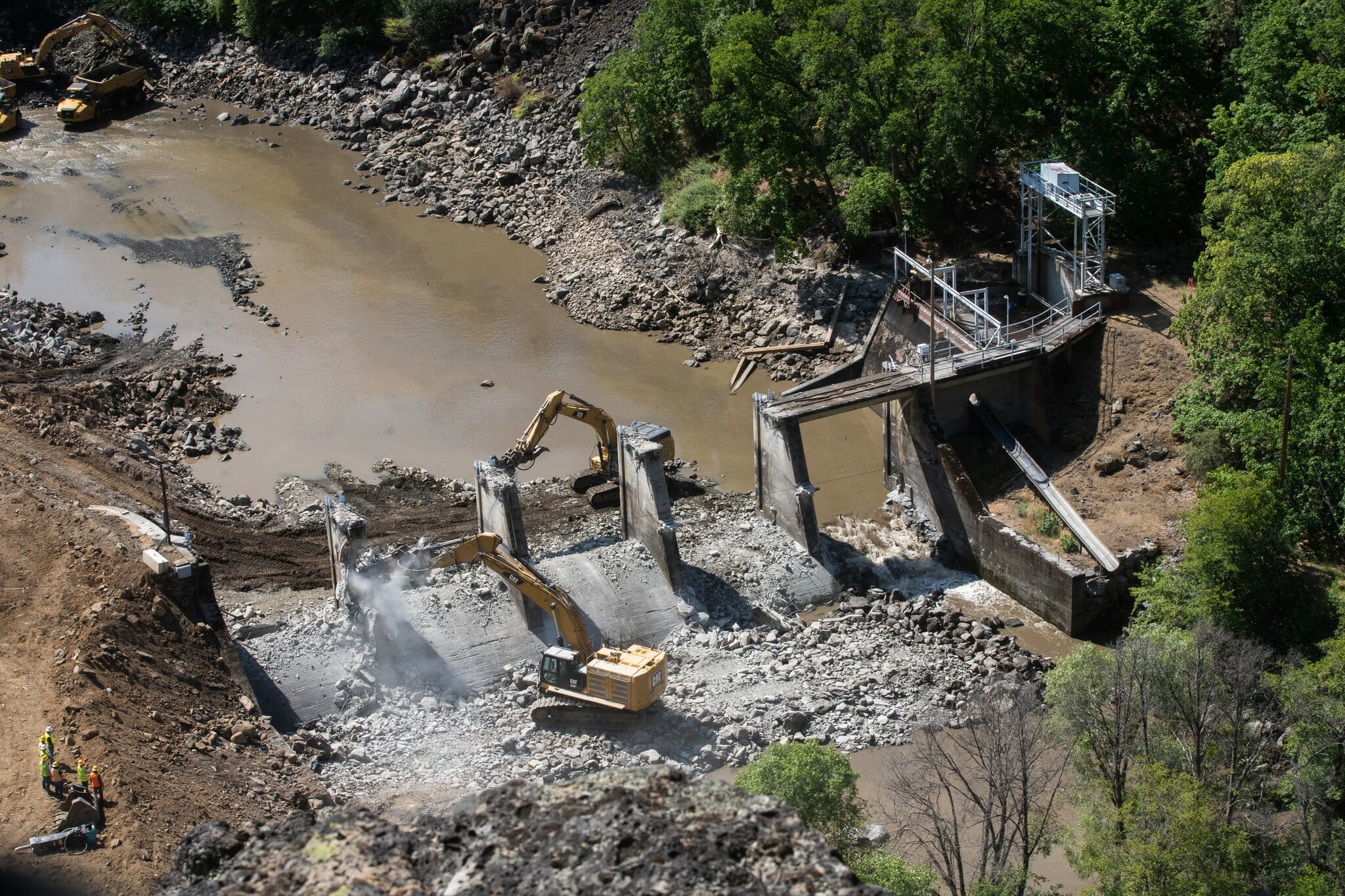 Areal view of cranes breaking a dam apart