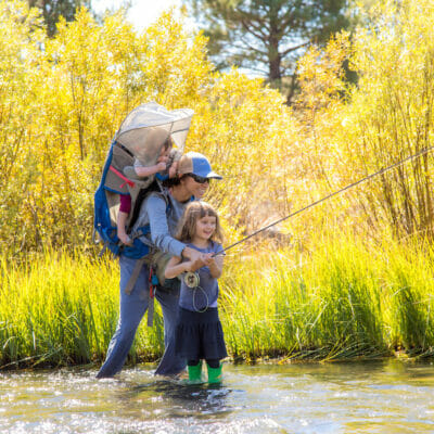 Woman and her two children fishing in a river